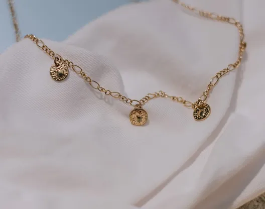 Fine silver chain with small charms on white fabric
