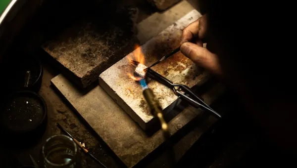 Torch flame soldering silver on a jeweller's workbench
